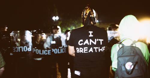 Protestor wearing I Can’t Breathe shirt facing police officers.