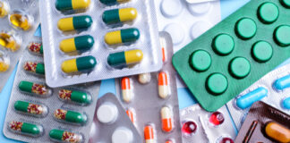 Various packs of colorful pills and capsules on blue background.