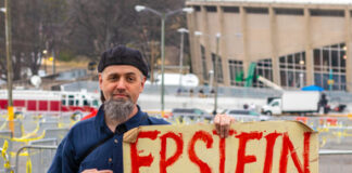 Man holding "Epstein didn't kill himself 2020" sign.