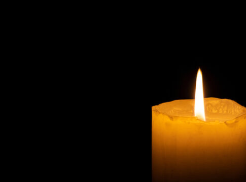 Lit candle in darkness.