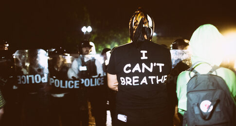 Protestor wearing I Can’t Breathe shirt facing police officers.