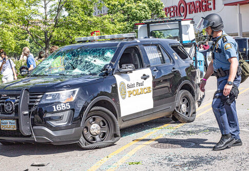 Damaged Saint Paul Police car with officer nearby.