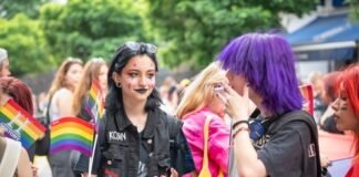 People at a pride event holding LGBTQ flags and signs.